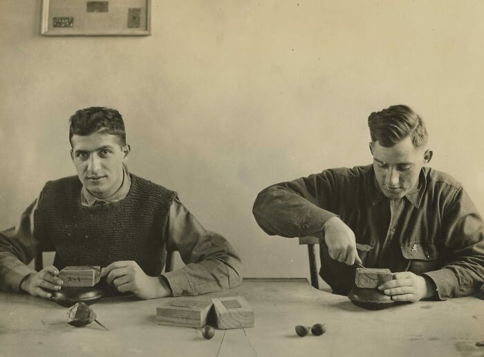 Two young men crafting wooden items at a table, revealing daily life beyond the WWI trenches.