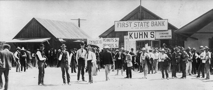 Crowd gathered in front of early First State Bank and market stalls, showcasing historic Vegas in the early 1900s.
