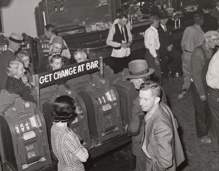 Vintage photo of people playing slot machines at a casino highlighting the birth of Vegas historic gambling era.