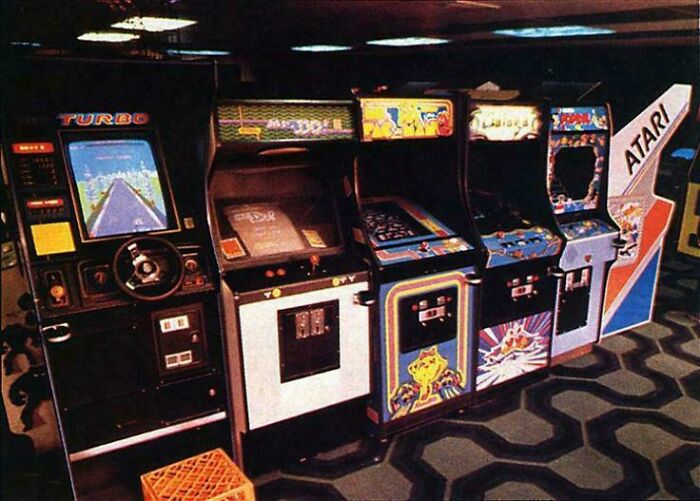 Vintage arcade machines lined up in a dimly lit room, evoking nostalgia and memories of old age for many people.