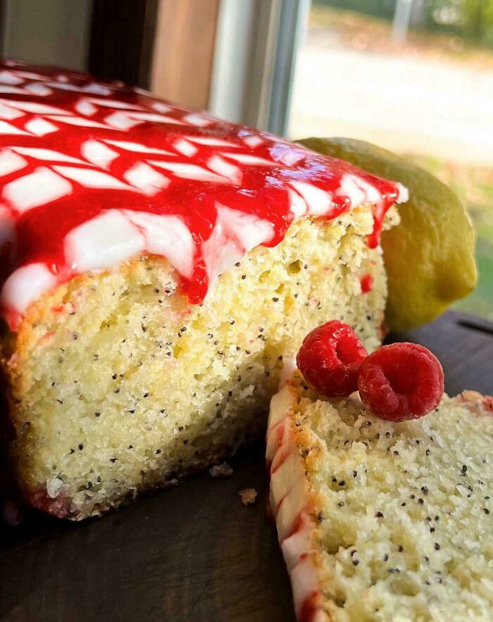 Close-up of a slice of baked goods with raspberry glaze and fresh raspberries, showcasing delicious homemade baked goods.