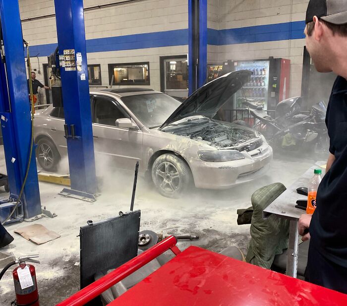 Car covered in fire extinguisher powder at repair shop, showing funny ways people learned their lesson in automotive mishaps.