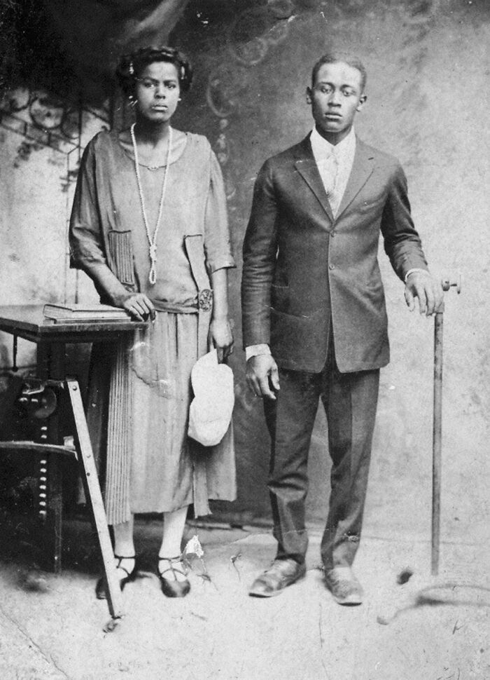 Vintage black and white photo of a man and woman standing formally, offering candid glimpses into the past history.