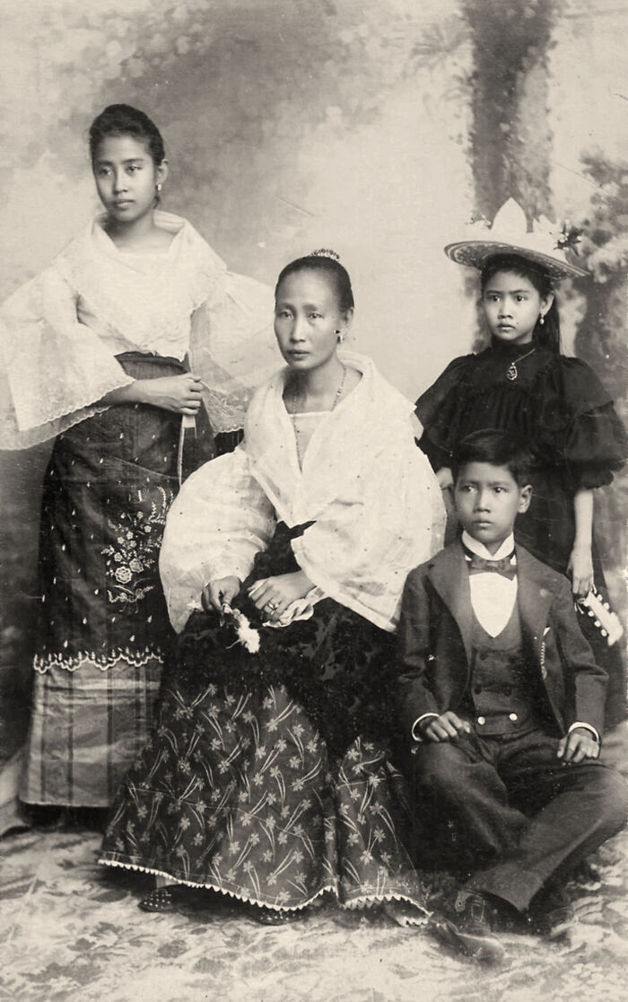 Old black and white photo of a Filipino family dressed in traditional and formal attire in the Philippines 1890s.