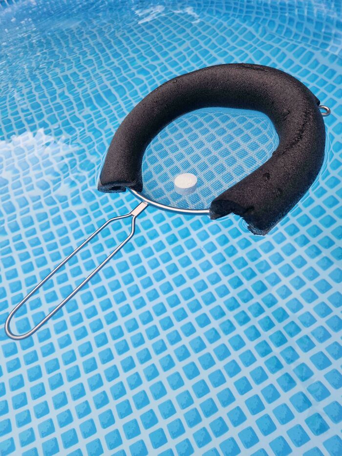 Pool skimmer with homemade float attached to metal frame, an ingenious creation from redneck engineers in a backyard pool.