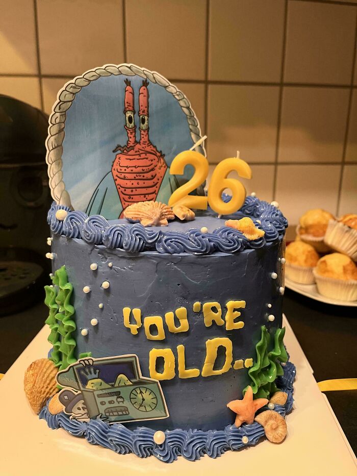 Birthday cake decorated with underwater-themed baked goods and blue frosting showing seashells and seaweed details.