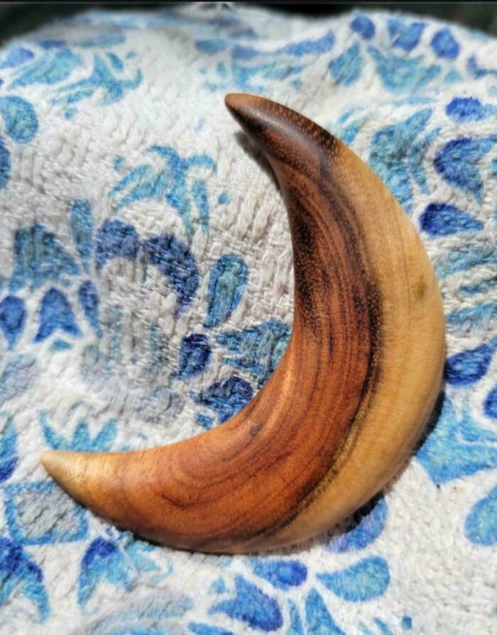 Smooth crescent-shaped wooden carving showcasing the skill of woodworkers in creating incredible projects with natural grain patterns.