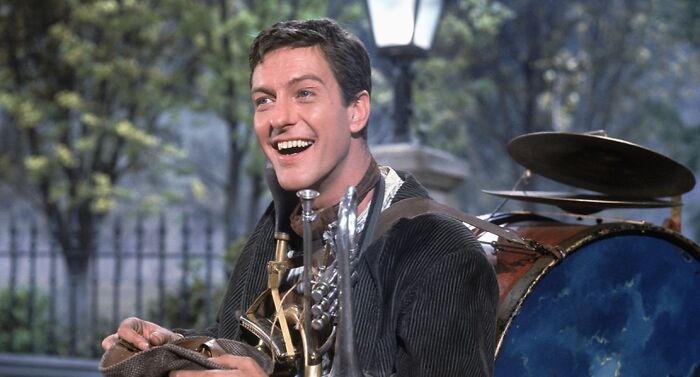 Actor playing a heartthrob character smiling outdoors with vintage musical instruments, iconic photo of classic actors.