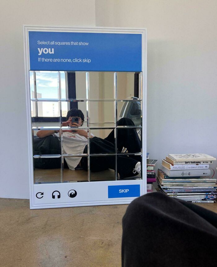 Mirror designed like a CAPTCHA puzzle with multiple square sections reflecting a person, showcasing smart designer innovation.