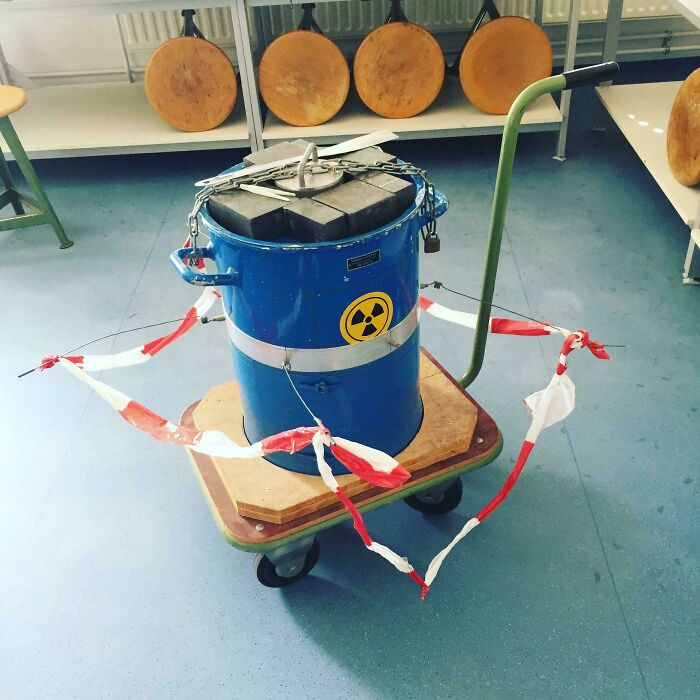 Blue barrel with a radioactive symbol secured with chains on a wooden platform cart, an example of redneck engineer creativity.
