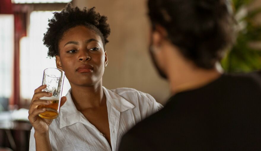 Young woman holding a glass and looking away, showing signs of emotional tension and soul ties in a casual setting. Young woman holding a glass and looking away, showing signs of emotional tension and soul ties in a casual setting.