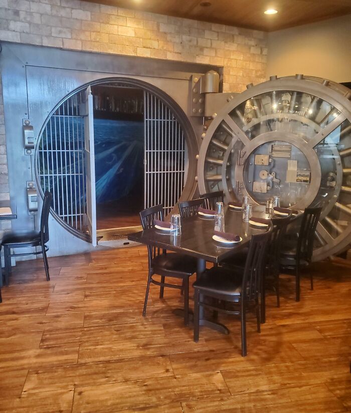 Creative bar interior with a large open vault door and a table set for six in a 5-star restaurant setting.