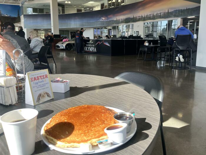 Modern bar and restaurant interior with creative dining setup featuring pancakes and coffee on a round table.