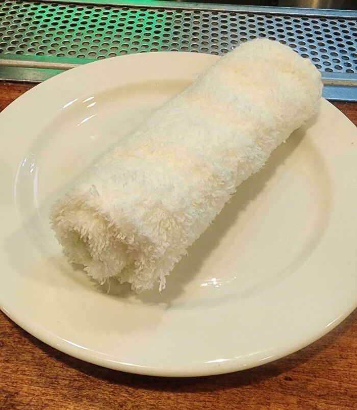 Rolled white towel on a plate at a bar showcasing creative presentation in bars and restaurants worldwide.