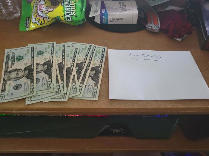 Envelope with Merry Christmas note and cash laid out on a desk, symbolizing generosity of wholesome kind neighbors. Envelope with Merry Christmas note and cash laid out on a desk, symbolizing generosity of wholesome kind neighbors.