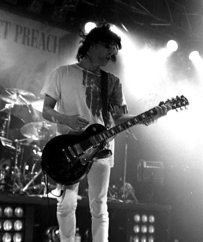 Young musician playing electric guitar onstage with dramatic lighting, representing chilling disappearances from the 90s era.