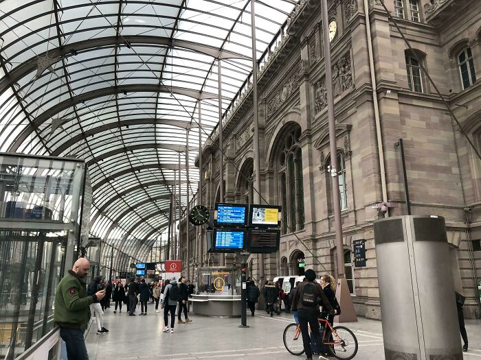 Old versus modern architecture shown in a busy train station blending historic stone walls with a glass and steel roof structure.