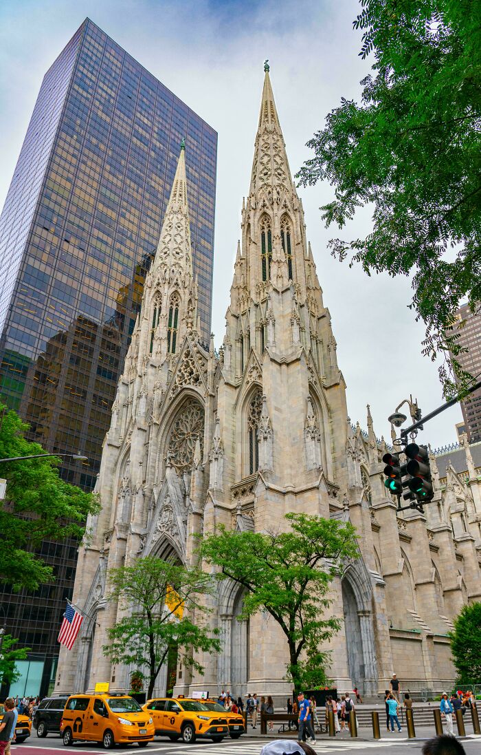 Gothic cathedral with detailed stonework contrasted by a modern glass skyscraper in an urban cityscape showcasing old versus modern architecture.