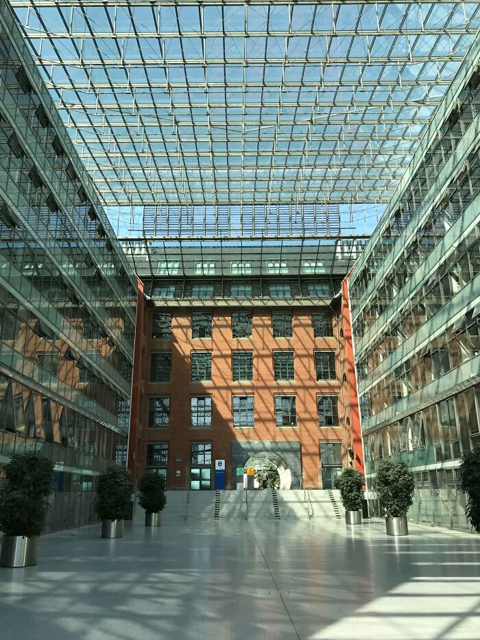 Interior view of old versus modern architecture with a glass ceiling and brick wall building under natural light.