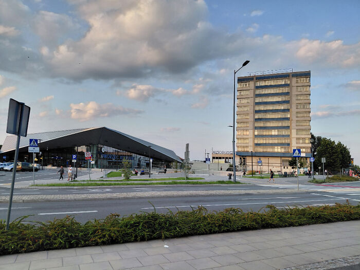 Old versus modern architecture with a historic tall building next to a contemporary low-rise structure under a cloudy sky.