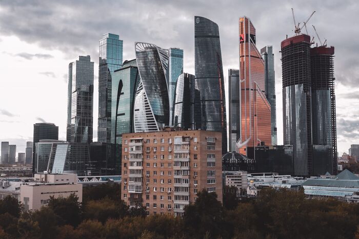 Old versus modern architecture shown through a contrast of a brick apartment building and sleek glass skyscrapers.