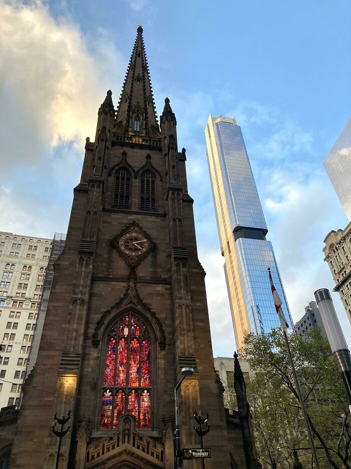 Gothic old architecture with stained glass contrasts against modern glass skyscraper under blue sky.