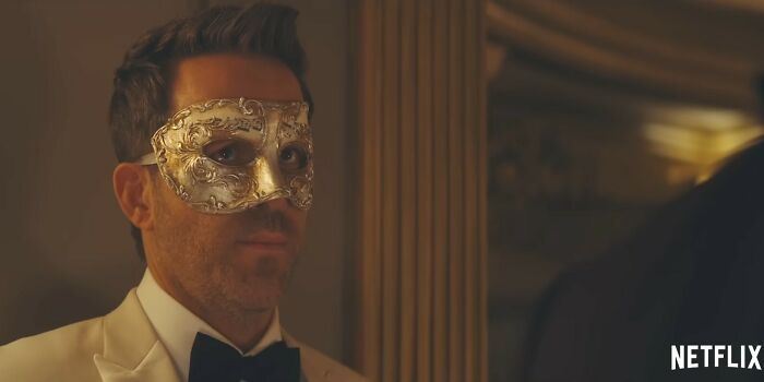 Man in white tuxedo wearing ornate mask at a formal event, representing Netflix movies that turned out to be letdowns.