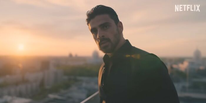 Man standing on rooftop at sunset in a scene from a Netflix movie listed among disappointing Netflix movies.