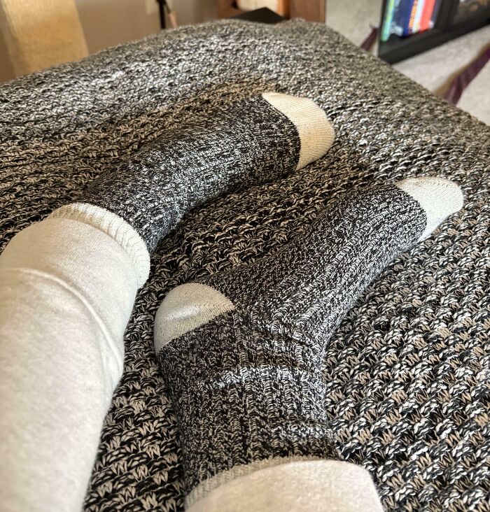 Grey and white socks blending perfectly with a matching knitted blanket, creating an impressive camouflage effect.