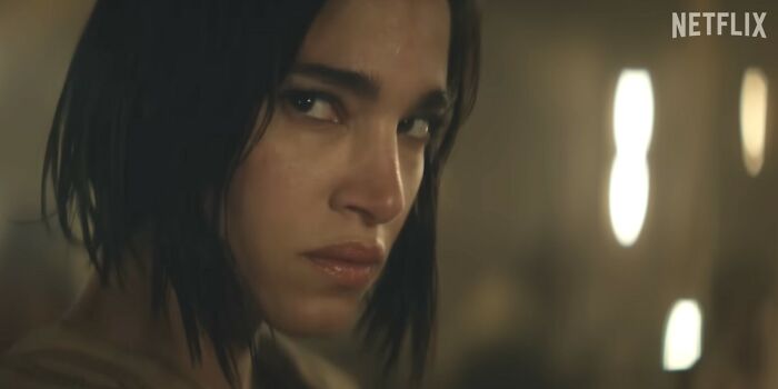 Close-up of a woman with intense expression in a dimly lit scene from a Netflix movie about disappointing Netflix movies.