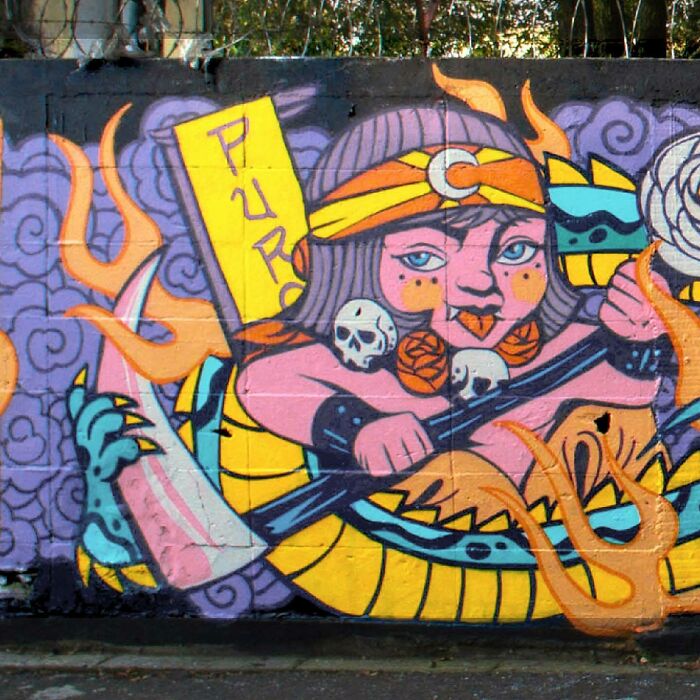 Colorful mural by Colombian artist SakoAsko featuring fantasy and reality elements with bold shapes and vibrant colors on a wall.