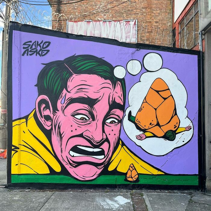Mural by Colombian artist SakoAsko showing a distressed man imagining a roasted figure blending fantasy and reality.