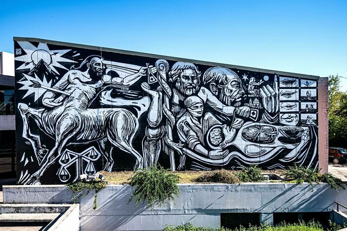 Mural by Colombian artist SakoAsko featuring black and white fantasy and reality elements in a striking outdoor artwork.