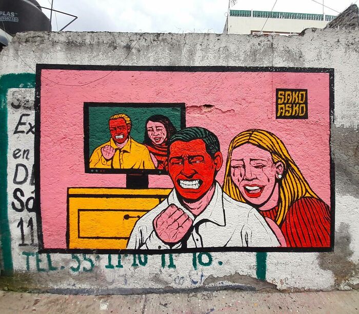 Mural by Colombian artist SakoAsko showing stylized smiling figures blending fantasy and reality in vibrant colors.