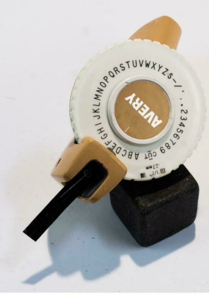 Vintage handheld label maker with rotating letter dial and a black printing lever, a nostalgic old school item to feel old.