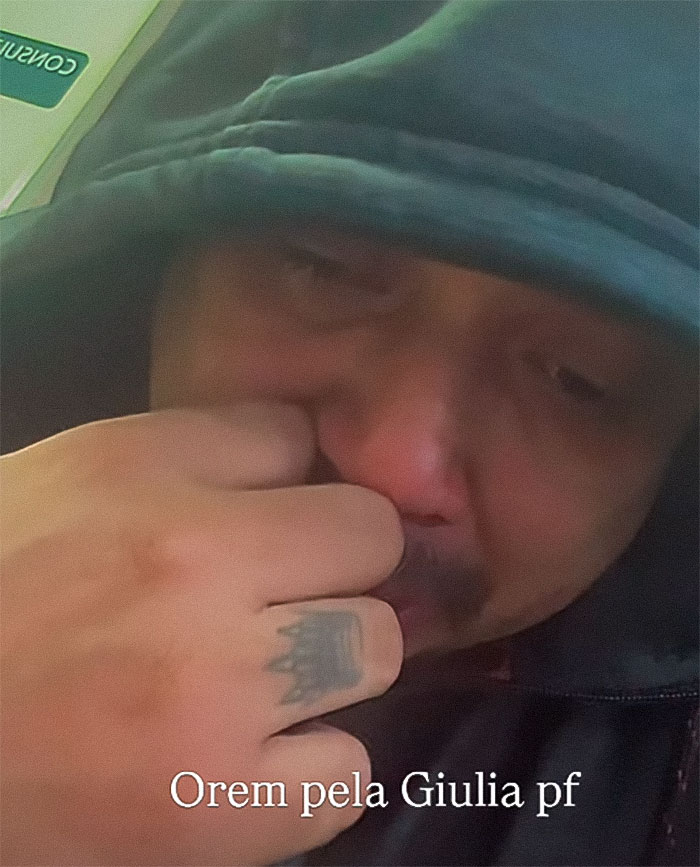 Man in a hooded jacket with a tattoo on his hand, appearing emotional, related to a 2-year-old drowning incident. Man in a hooded jacket with a tattoo on his hand, appearing emotional, related to a 2-year-old drowning incident.