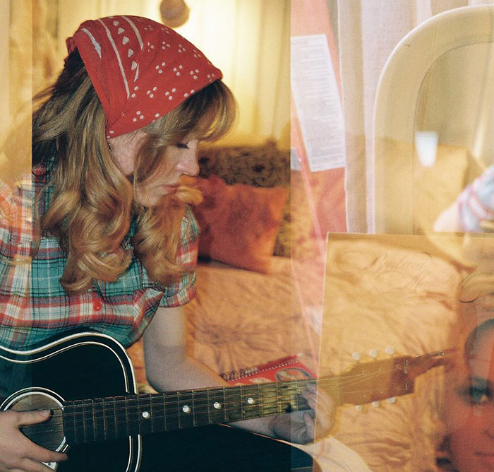 Sydney Sweeney playing guitar indoors with a red bandana and plaid shirt, reflecting a vintage, cozy atmosphere. Sydney Sweeney playing guitar indoors with a red bandana and plaid shirt, reflecting a vintage, cozy atmosphere.