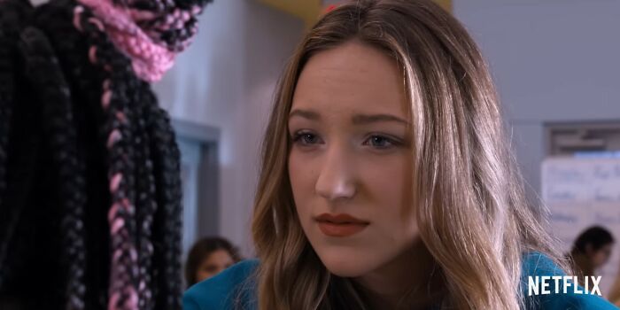 Close-up of a woman in a blue shirt looking concerned in a Netflix scene from movies that turned out to be letdowns.