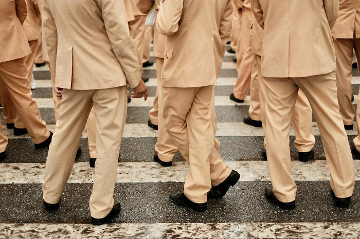 Group of people wearing beige suits walking across a street, one of the candid everyday moments from Asia captured by photographer Gil Kreslavsky