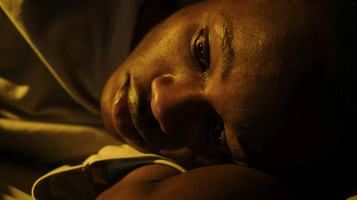 Close-up of a person lying down in dim light, reflecting the unsettling signs of soul ties still gripping someone.
