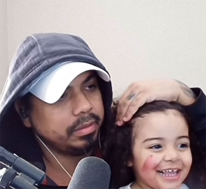 Man in a hoodie streaming with a young child, highlighting tragic 2-year-old drowning during dad's live stream incident. Man in a hoodie streaming with a young child, highlighting tragic 2-year-old drowning during dad's live stream incident.
