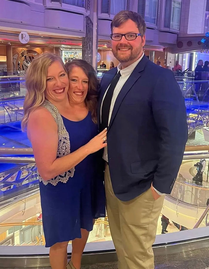 Conjoined twins Abby and Brittany Hensel posing indoors with a man, sparking buzz after being seen with a newborn baby. Conjoined twins Abby and Brittany Hensel posing indoors with a man, sparking buzz after being seen with a newborn baby.