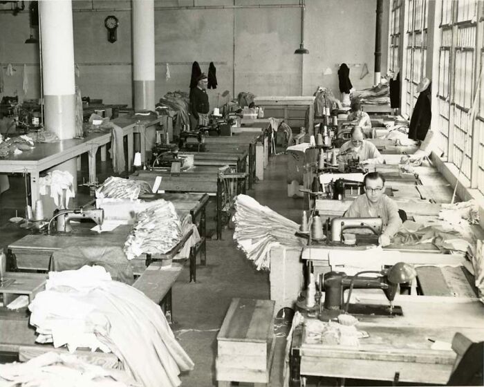 Black and white photo showing prisoners using sewing machines in a workshop, illustrating harsh reality of life on Alcatraz.