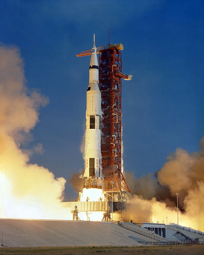 Saturn V rocket launching from platform, showcasing record-breaking inventions moving at mind-blowing speeds in space travel.