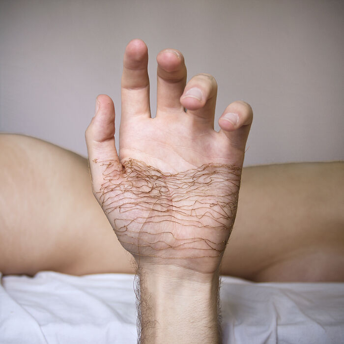 A close-up of a hand with delicate landscape stitched onto the skin using fine thread art.