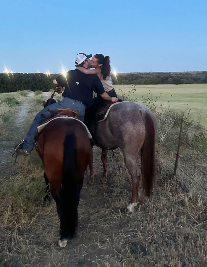 Couple riding horses on a trail at dusk, sharing a kiss, with open fields and clear skies in the background. Couple riding horses on a trail at dusk, sharing a kiss, with open fields and clear skies in the background.