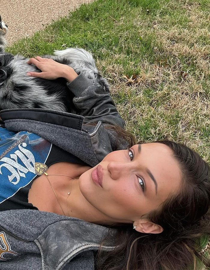 Bella Hadid posing outdoors lying on grass with dog, showing a casual, natural look for new perfume launch. Bella Hadid posing outdoors lying on grass with dog, showing a casual, natural look for new perfume launch.