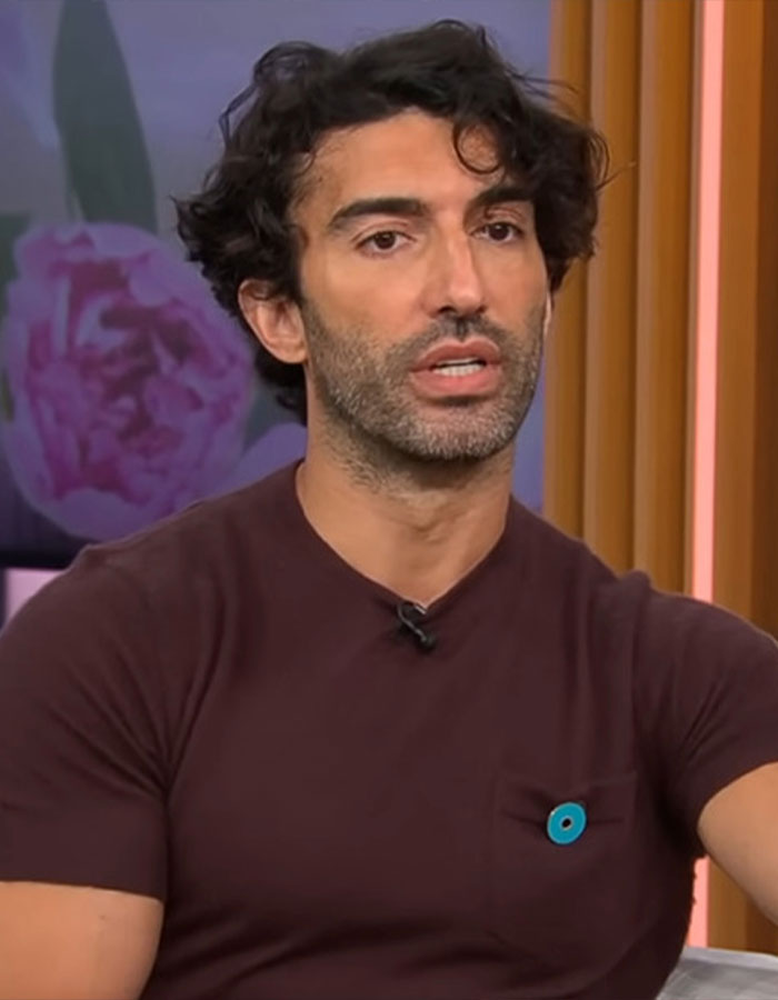 Man with curly hair and beard wearing a brown shirt, speaking during an interview about Blake Lively rom-com role. Man with curly hair and beard wearing a brown shirt, speaking during an interview about Blake Lively rom-com role.