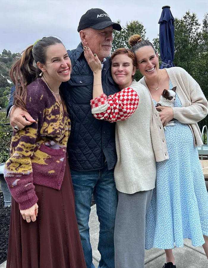 Bruce Willis with family outdoors, smiling and embracing, highlighting update from his wife amid dementia battle and separate living. Bruce Willis with family outdoors, smiling and embracing, highlighting update from his wife amid dementia battle and separate living.
