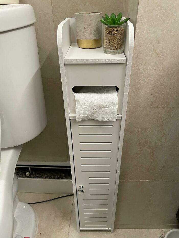 Compact bathroom storage cabinet holding toilet paper and plants, showcasing low-lift, high-impact bathroom improvements.